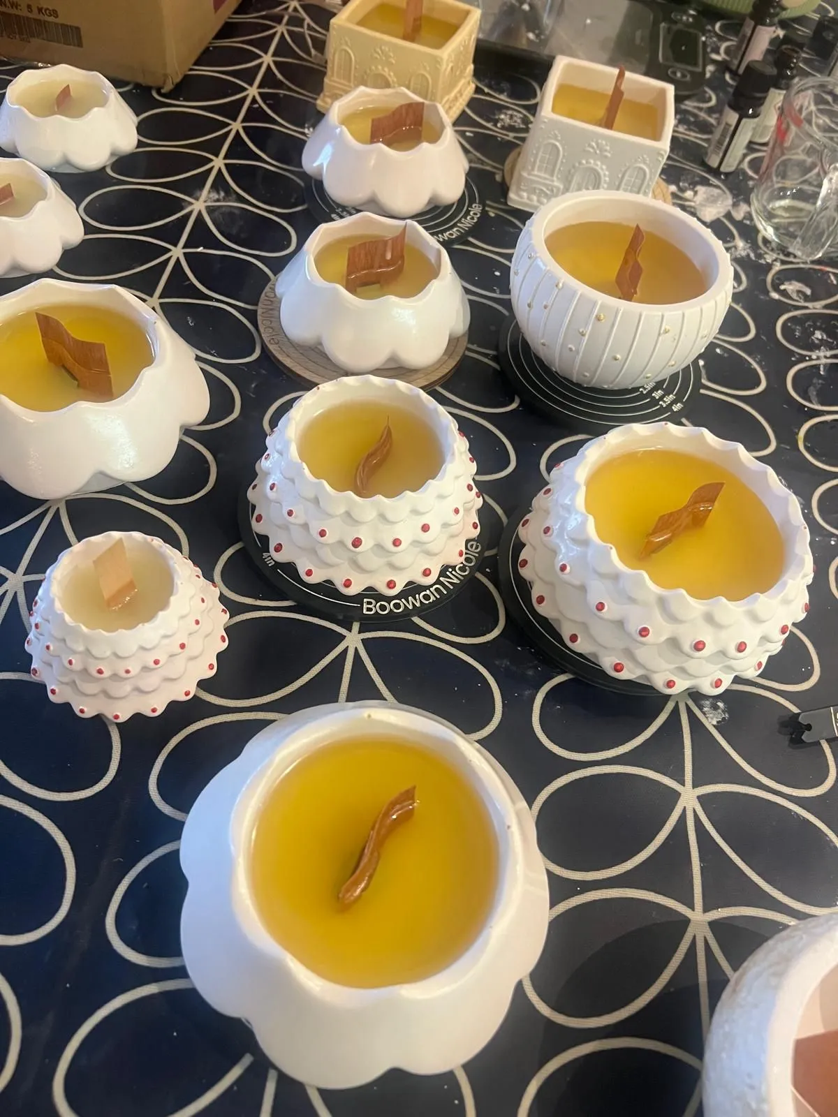 Handmade candles curing in ceramic vessels with wooden wicks